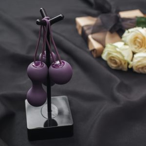 Purple kegel Balls hanging on a stand against a background of a black fluid proof sheet
